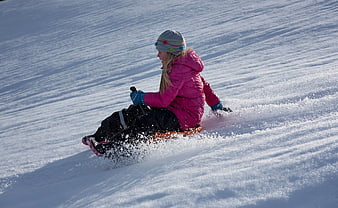 Girl sledding down snowy hill in winter