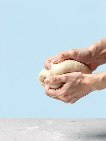 Hands kneading dough on blue background