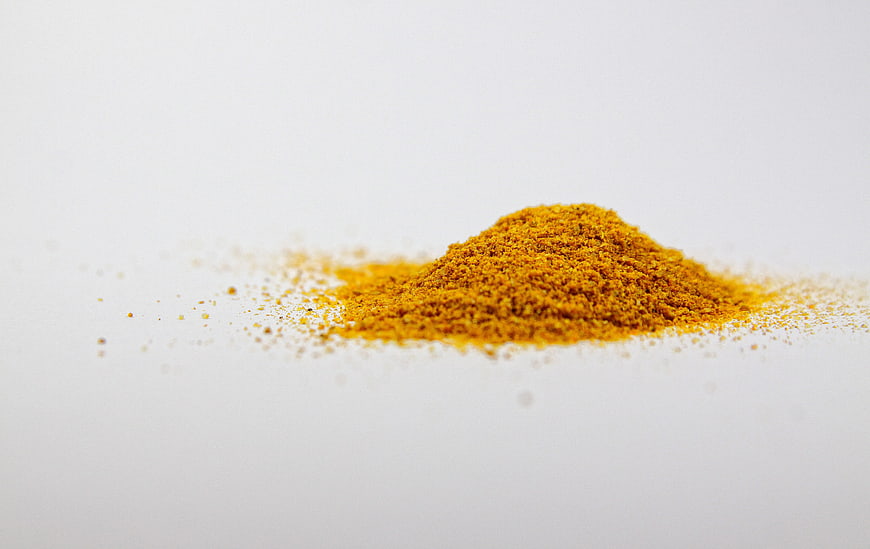 Pile of yellow turmeric spice powder on white background