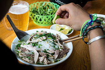 Close-up of hands squeezing lime into Vietnamese Pho soup