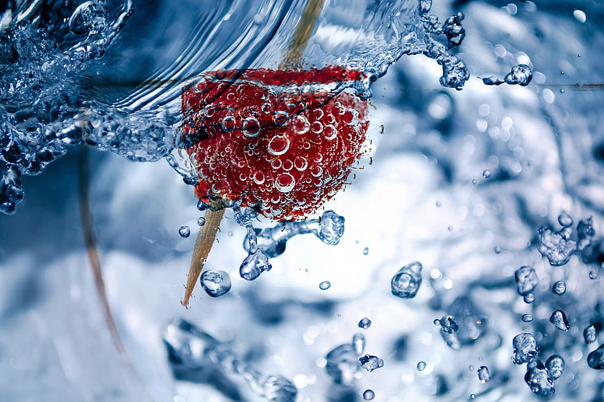 Close-up of red raspberry submerged in splashing water