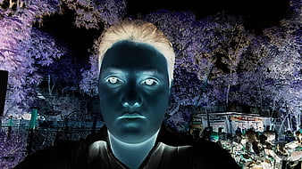 Glowing blue face with white eyes in surreal night scene