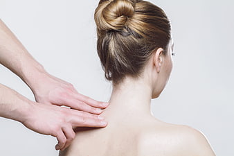 Woman receiving neck and shoulder massage from behind