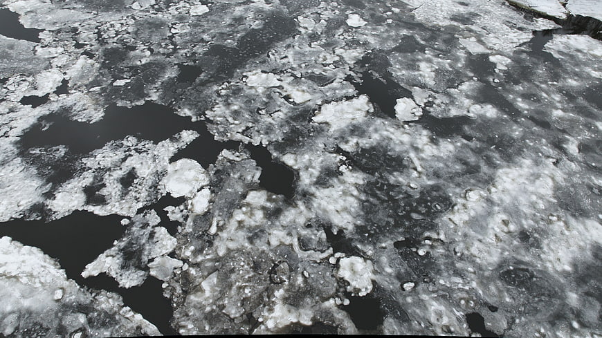 Abstract texture of melting ice and slush on dark water surface