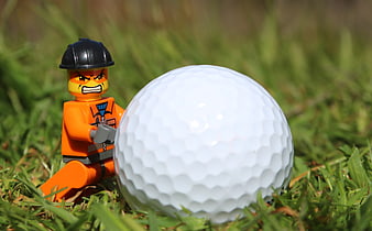 Angry Lego Figure Crouching Beside Large White Golf Ball On Grass