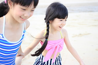 Two happy young girls holding hands on a sunny beach