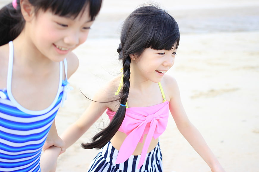 Two happy young girls holding hands on a sunny beach