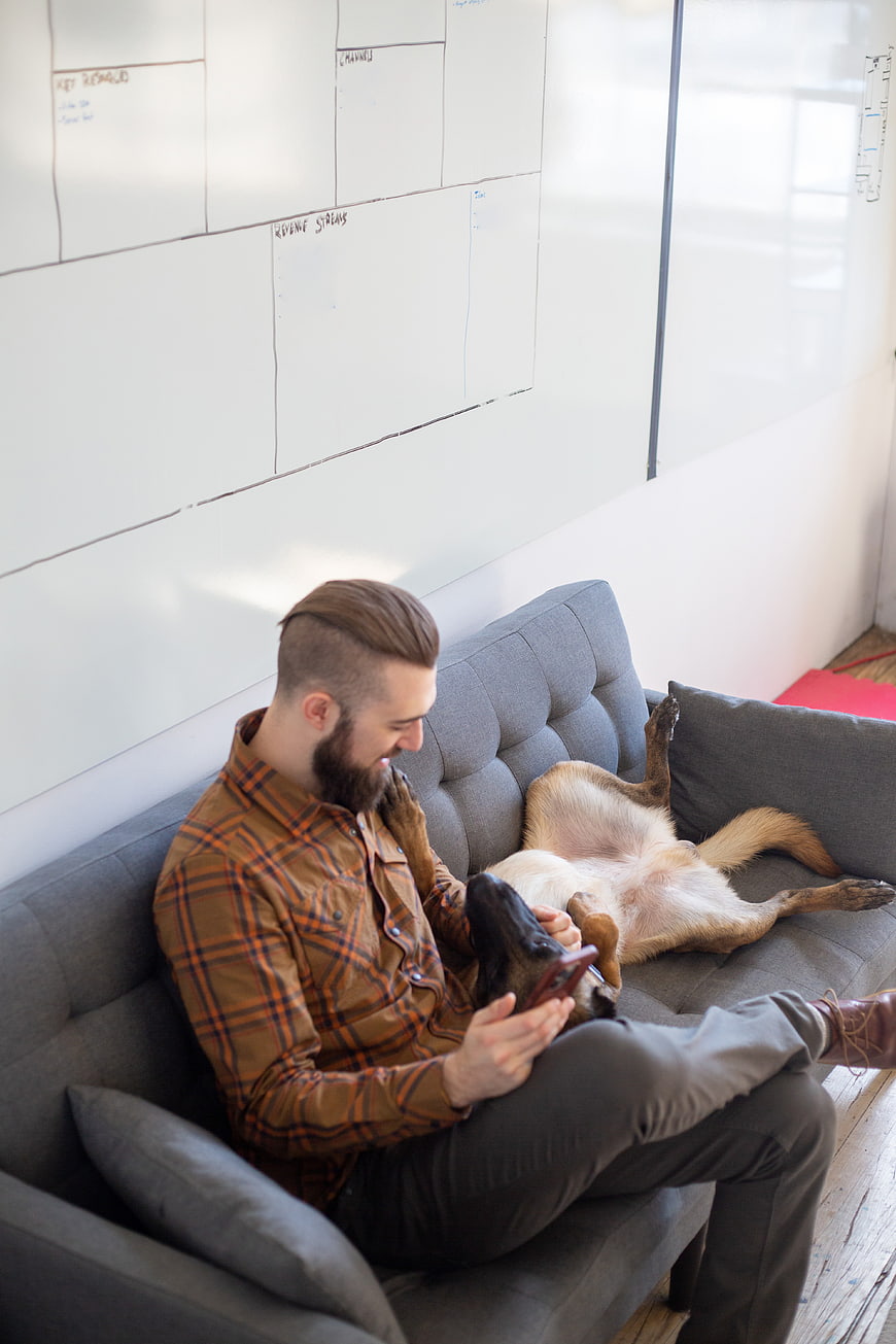 Man with beard relaxing on couch with playful dog