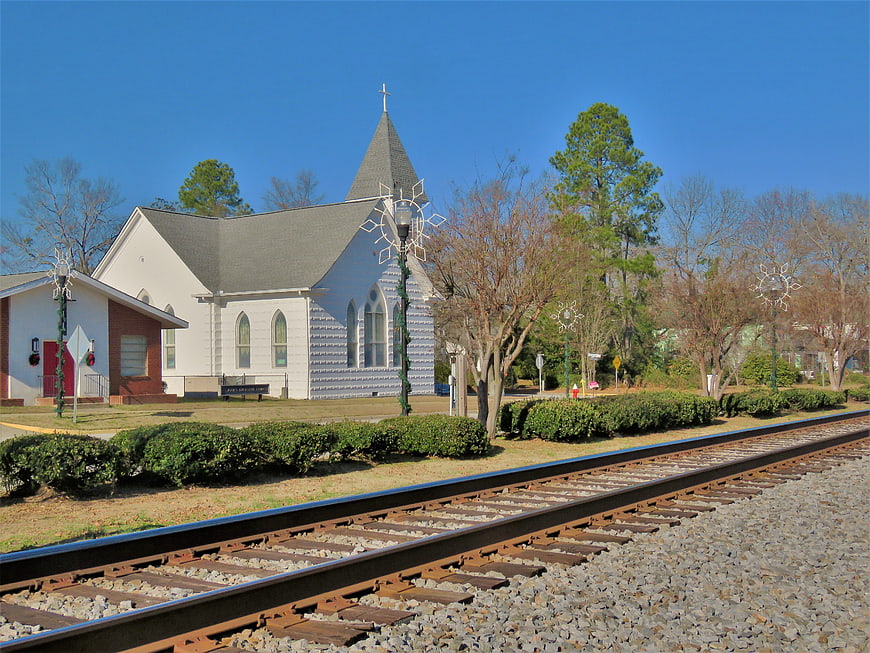 White church with steeple beside railroad tracks