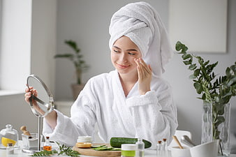 Woman applying skincare cream while looking in mirror