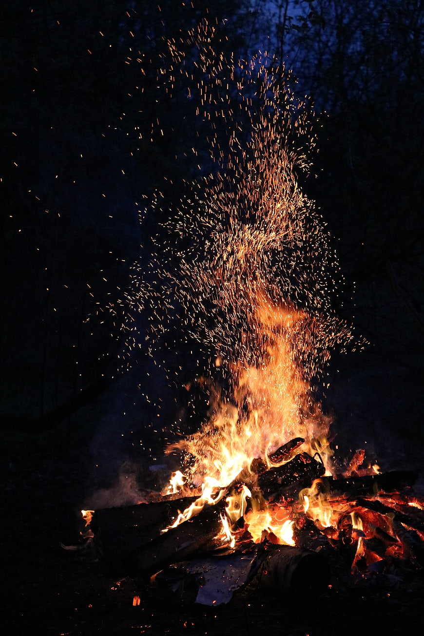 Bonfire with Sparks Flying at Night in Forest
