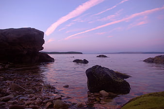 Serene Coastal Landscape with Pink Clouds and Rocky Shore
