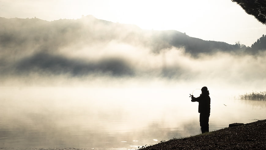 Silhouette of Fly Fisherman in Misty Morning Landscape