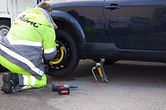 Roadside mechanic changing car tire with impact wrench