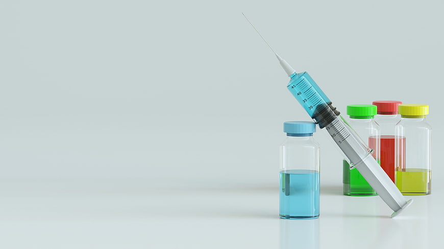 Medical syringe and colorful medicine bottles on white background