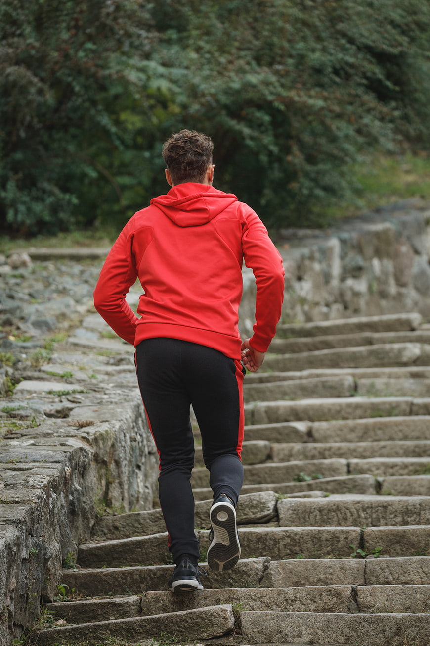 Man in Red Hoodie Running Up Stone Stairs Outdoors
