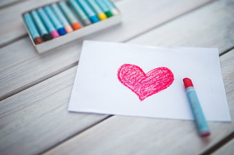 Red crayon heart drawing on white paper with pastel crayons