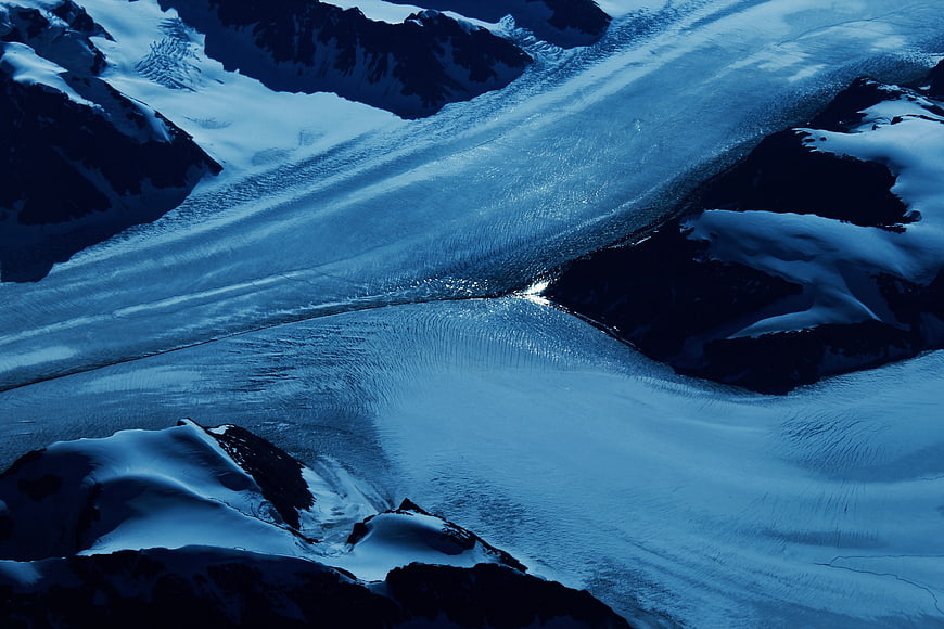 Aerial View of Blue Glacier Flowing Through Snowy Mountains