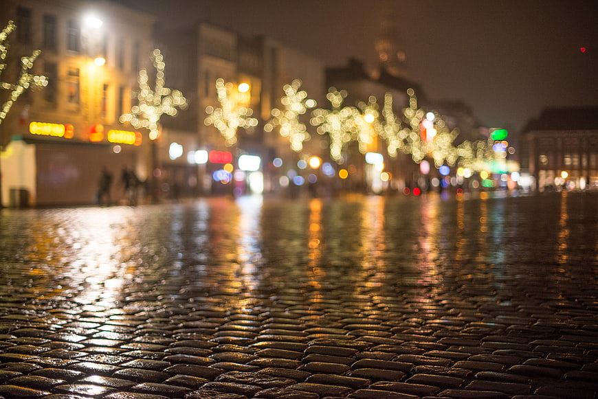 Wet cobblestone street with bokeh lights at night