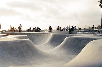 Concrete skate park with ramps and people at sunset