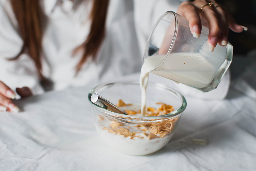 Woman Pouring Milk into Cereal Bowl for Breakfast