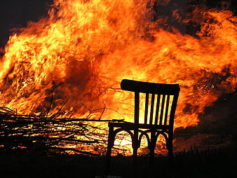 Silhouette of a wooden chair in front of a massive fire