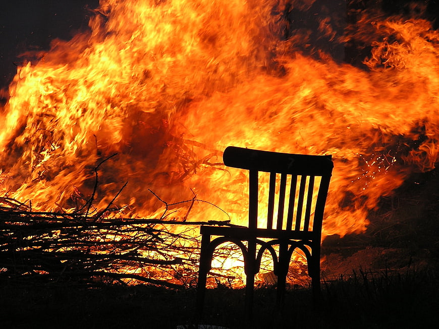 Silhouette of a wooden chair in front of a massive fire