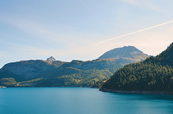 Serene Alpine Lake with Forested Mountains and Blue Sky