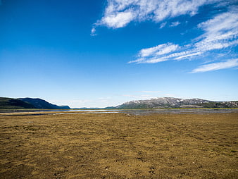 Wide landscape of a tidal flat with mountains and blue sky