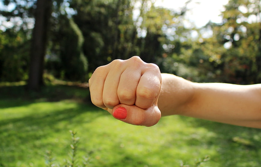 Close-up of clenched fist with red nail polish outdoors