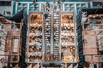 Aerial view of busy escalators and dining area in modern shopping mall