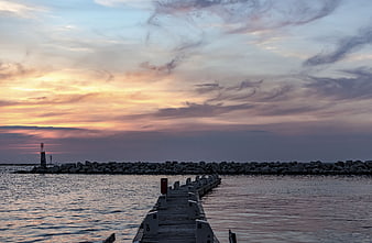 Sunset over wooden pier and rocky breakwater