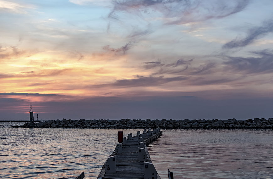 Sunset over wooden pier and rocky breakwater