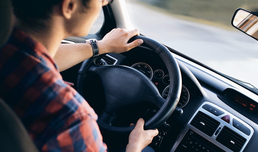 Man Driving Car on Road with Hands on Steering Wheel