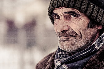 Close-up portrait of elderly man in winter hat and scarf