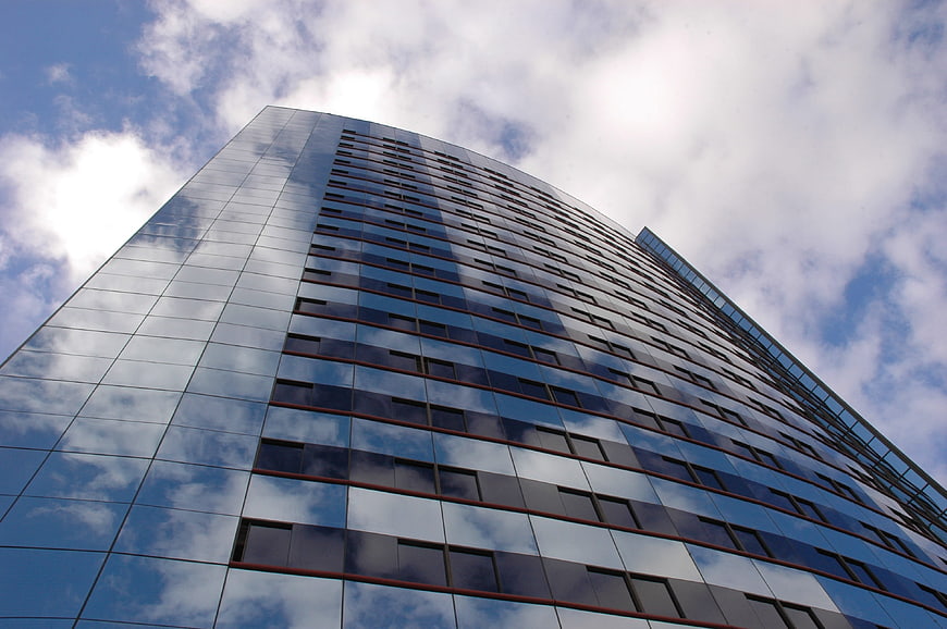 Low angle view of modern glass skyscraper reflecting blue sky