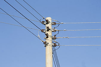 Wooden utility pole with power lines against blue sky