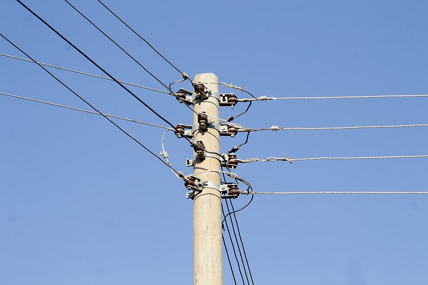 Wooden utility pole with power lines against blue sky