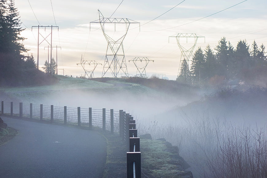 Foggy rural road with power lines and fence