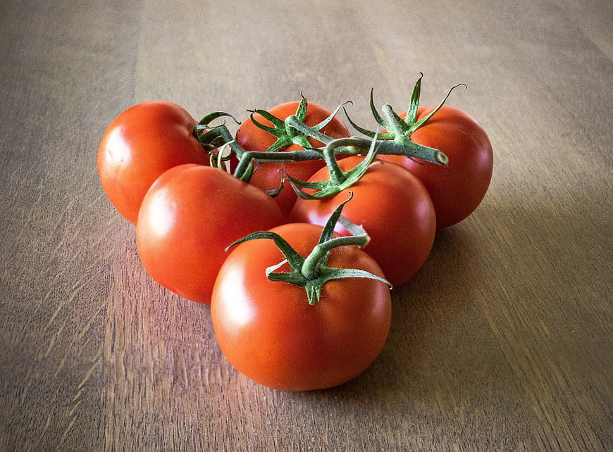 Fresh Red Tomatoes on Vine on Wooden Table