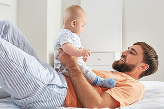 Happy Father Playing with Baby on Bed