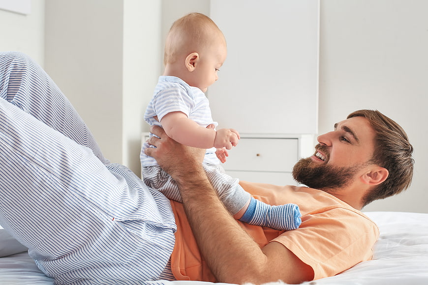 Happy Father Playing with Baby on Bed