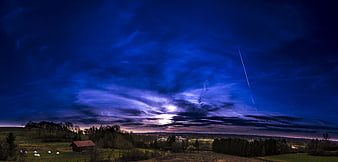 Dramatic twilight landscape with barn and moonlit clouds