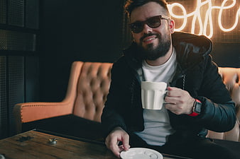 Smiling man with sunglasses drinking coffee in a cafe