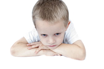 Sad young boy looking down with crossed arms on white background