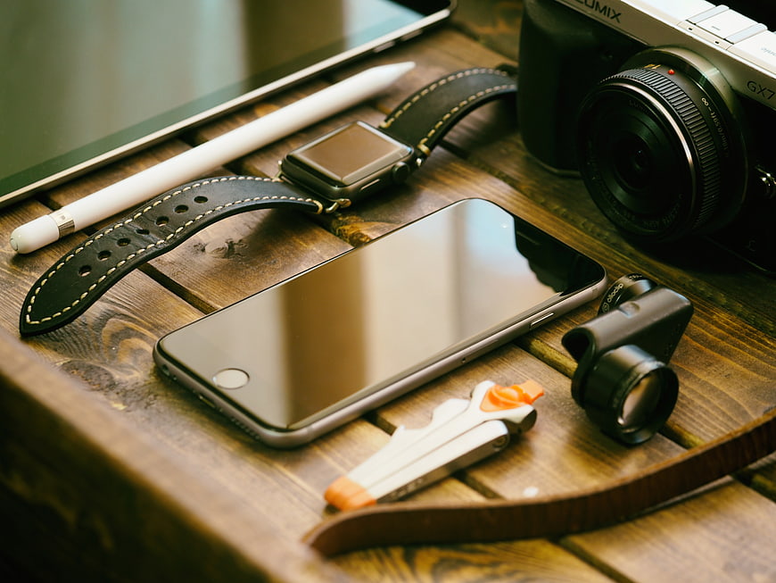 Tech gadgets on wooden table with camera and smartphone