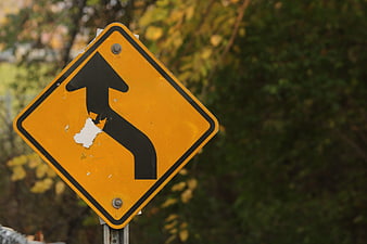 Yellow Road Sign with Curved Arrow and Torn Sticker