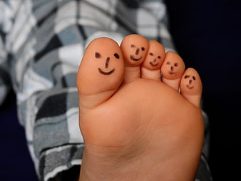 Cute child's foot with smiley faces drawn on toes