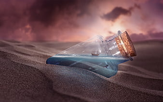 Glass bottle with miniature ship on desert sand at sunset