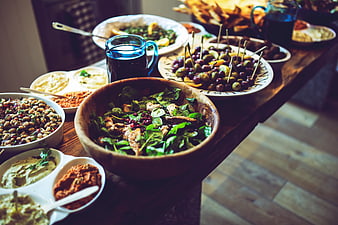 Rustic wooden table with Mediterranean mezze platter and salads